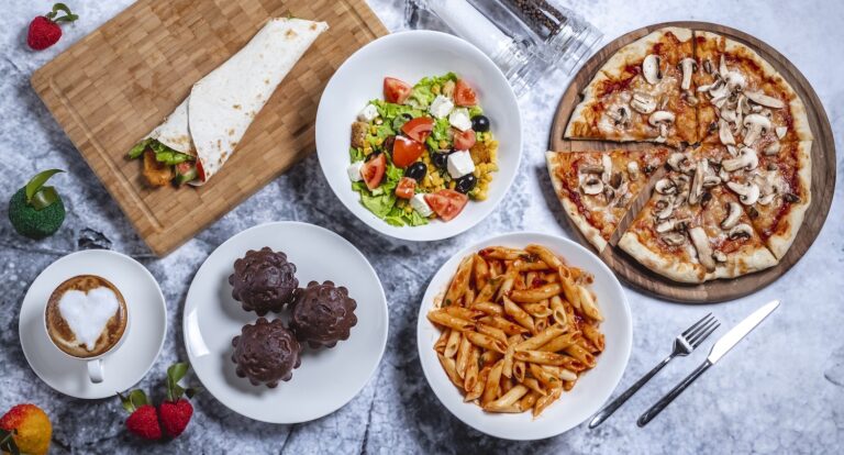 A variety of delicious foods including pizza, pasta, salad, coffee, and desserts on a table.