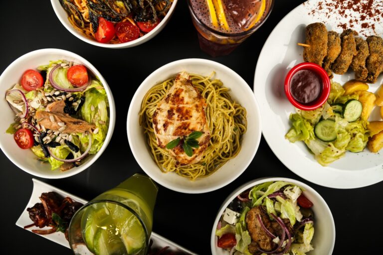 A variety of colorful dishes including salads and pasta with grilled chicken.